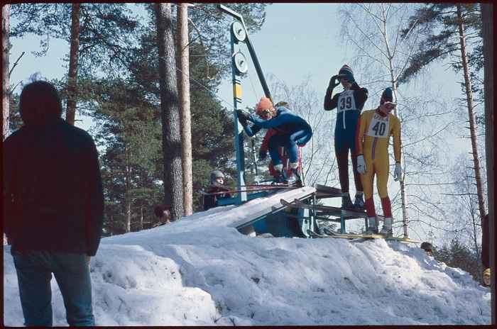 Mäkihyppykilpailut Huhtiniemessä Lappeenrannassa; kilpailija aloittamassa hyppysuoritustaan, 1970-luvun urheilumuodin mukaisissa hyppyasuissa. Kuva: Mikonsaari, Aarne A.